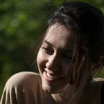 A joyful woman enjoying the sunlight outdoors, captured in natural lighting.